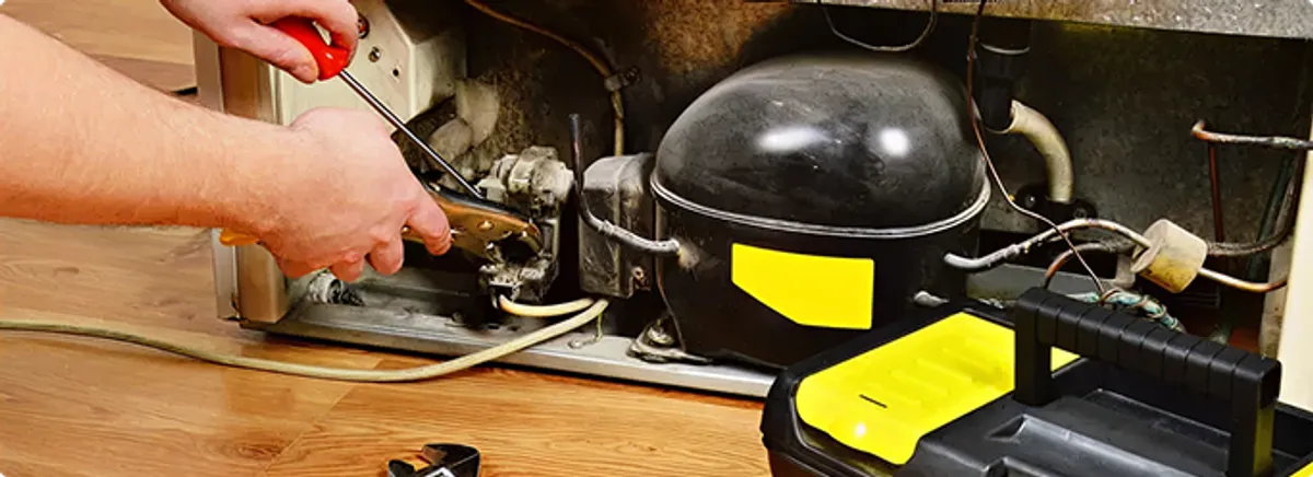 Refrigerator repair technician fixing the compressor and wiring in Deerfield Beach, FL