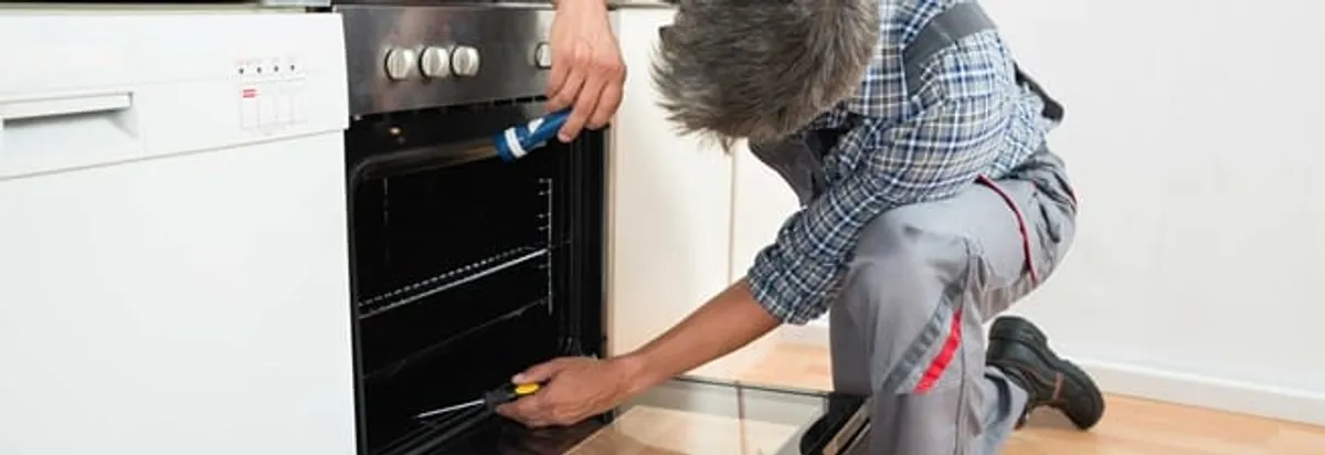 Oven repair technician inspecting and servicing an electric oven in Fort Lauderdale, FL