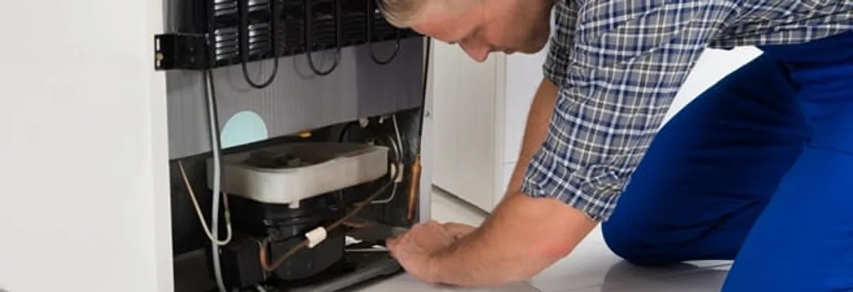 Refrigerator repair technician servicing the compressor and condenser area in Fort Lauderdale, FL